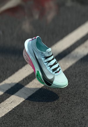 Baskets de course bleu clair avec une tige texturée, lacets noirs et une semelle rose et verte. Présente un design élégant et un branding visible sur le côté.
