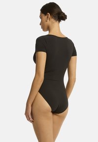 Body nero con maniche corte, texture liscia, aperture a gamba alta e un design aderente, mostrato da dietro.