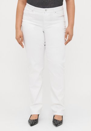 Weiße Jeans im Straight-Leg-Design, ausgestattet mit zwei Vorderaschen und einem Knopfverschluss. Tragen mit spitzen schwarzen, mit Nieten besetzten Absätzen.