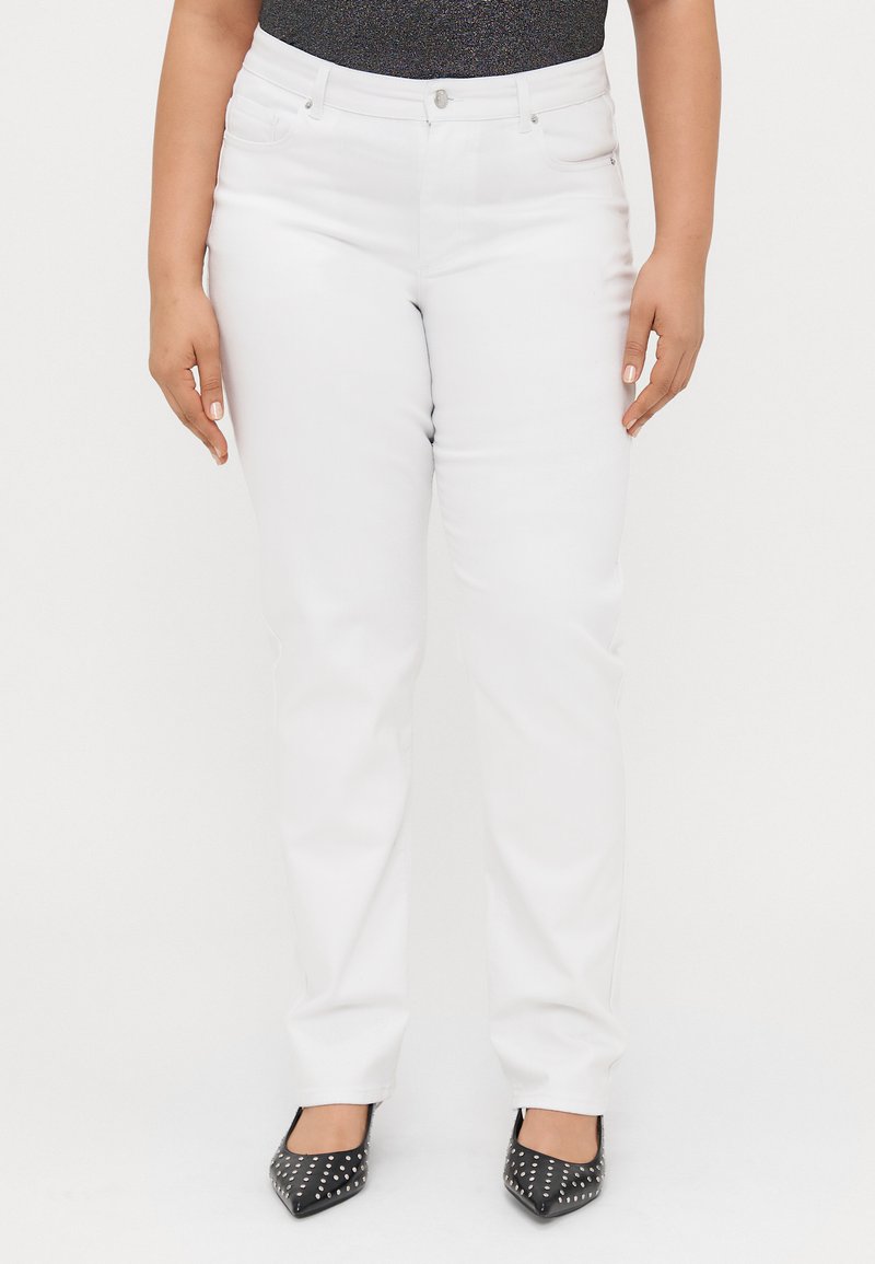 Λευκό τζιν παντελόνι με ίσια γραμμή, διαθέτοντας δύο μπροστινές τσέπες και κλείσιμο με κουμπί. Φοριέται με μαύρες μυτερές ψηλοτάκουνες γόβες με τρουκ.