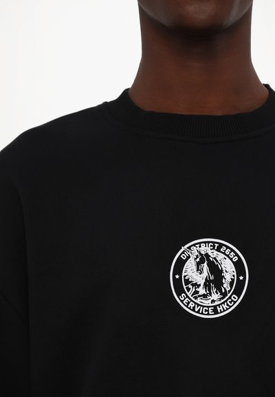 Sweat-shirt noir avec col côtelé ; arbore un logo circulaire blanc avec "District 2650" et "Service HKCO", représentant une licorne.