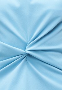 Απαλό γαλάζιο ύφασμα μαζεμένο και στριμμένο στο κέντρο, δημιουργώντας ομαλές πτυχές που ακτινοβολούν προς τα έξω.