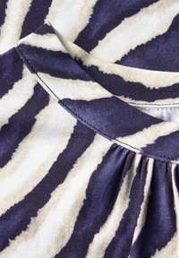 Tessuto testurizzato con un motivo a strisce di zebra blu navy e avorio, con uno scollo rotondo e dettagli arricciati lungo la cucitura.