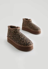 Kožené kotníkové boty s leopardím vzorem mají hnědou umělou kožešinu, zaoblenou špičku a platformovou podrážku s texturovaným gripem.