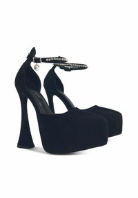 Décolleté in suede nero con plateau e alti tacchi a spillo, cinturini alla caviglia decorati con strass e punta arrotondata.