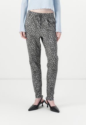 Obcisłe spodnie w panterkę ze ściągaczem w pasie, noszone z czarnymi butami na obcasie typu slingback oraz jasnoniebieskim krótkim topem.