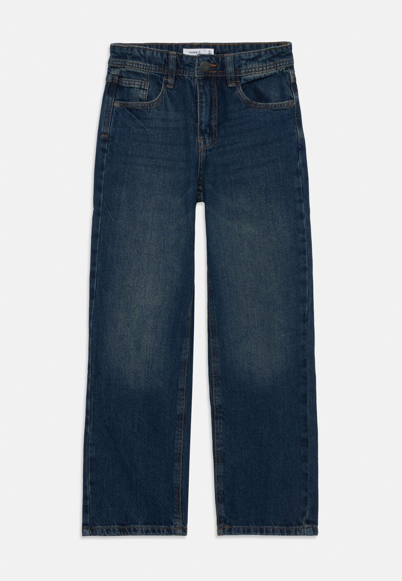 Džínsy v tmavomodrej farbe, s rovnými nohavicami, piatimi vreckami a kontrastným prešívaním. Tkanina má jemnú štruktúru s vyblednutými miestami.