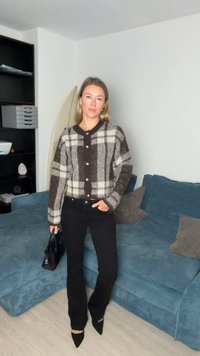 Hnedý a krémový károvaný kardigán s veľkými gombíkmi, v kombinácii s čiernymi rozšírenými nohavicami a malou čiernou kabelkou; hladká textúra, voľný strih.