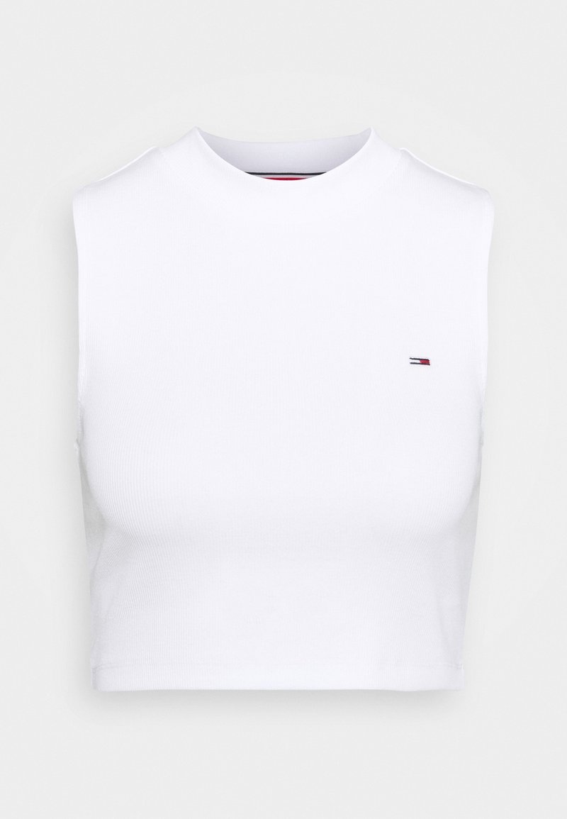 Haut court sans manches blanc avec encolure ronde et petit logo rouge, blanc et bleu sur le côté gauche de la poitrine.