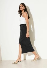 Mustast teksast midi seelik esilõhikuga, millel on vööaasad ja taskud. Sobitatud beežide madu-mustriliste tagasitõmmatavate kontsakingadega.