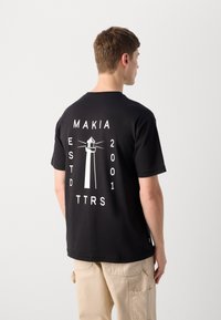 Must mustern, mille valge tuletorniga graafika ja tekstiga seljal, lühikeste käistega ja ümar kaelus. Klassikaline lõige.