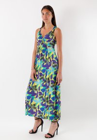 Maxiklänning med ett livligt botaniskt mönster i blått, grönt, gult och lila, med en omslagdesign, justerbara axelband och en luftig silhuett.