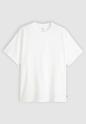 T-shirt branca de manga curta, feita de algodão, com decote redondo. Apresenta um discreto detalhe de logotipo em relevo na frente e uma etiqueta vermelha na bainha.
