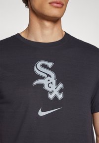 T-shirt de algodão preta com um grande logotipo cinza "Sox" e símbolo da Nike no frente, decote redondo e mangas curtas.