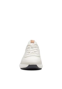 Vue de face d'une basket blanche à lacets avec une languette beige et une partie de semelle extérieure noire.