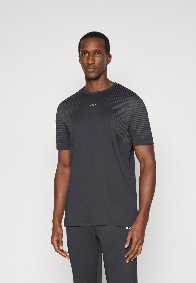 Μαύρο αθλητικό μπλουζάκι με ραγλανά μανίκια, διαθέτει υφασμάτινες οριζόντιες ρίγες στους ώμους. Το λογότυπο είναι τοποθετημένο στο κέντρο του στήθους.