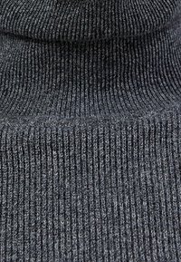 Maglione a collo alto a costine grigio scuro con un morbido e testurizzato lavorato a maglia. Presenta un colletto alto e un design aderente.