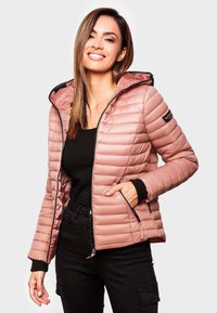 Ljust rosa pufferjacka med horisontell quiltad textur, svarta accenter, dragkedjefickor och huva. Matchad med en svart topp och mörka byxor.