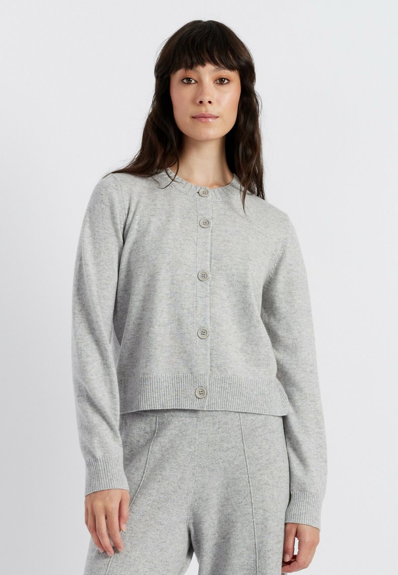 Cardigan grigio chiaro realizzato in morbido tessuto a maglia, con scollatura rotonda, chiusura frontale con sei bottoni e maniche e orlo a coste.