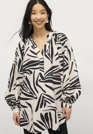 Langarmblouse in lichtbeige met gedurfde zwarte dierlijke patronen, voorzien van een halve knoopsluiting en gathered mouwen.