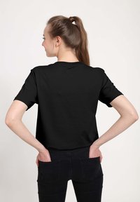 Sort t-shirt med korte ærmer og rund halsudskæring, lavet af glat bommateriale, afslappet pasform, og uden synlige logoer eller design.