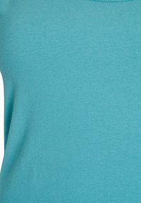 Teal värvi keha lähedal istuv jersest valmistatud ülemine osa, millel on ümar kaelus ja sile tekstuur, esitleb ribakujulist mustrit. Lihtne ja ühtlane disain.