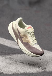 Lightweight running shoe with a beige upper and textured brown accents. Features a cushioned sole and pronounced branding on the side.