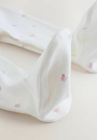 Fehér zokni puha anyagból, finom virágmintával, kis rózsaszín rózsákkal és zöld levelekkel. Simas textúra.