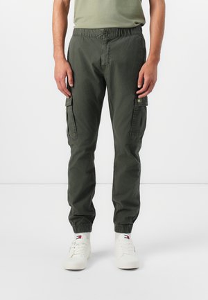 Khaki cargo pants with elastic waistband and cuffs, featuring side pockets and a soft, breathable fabric. Worn with white sneakers.