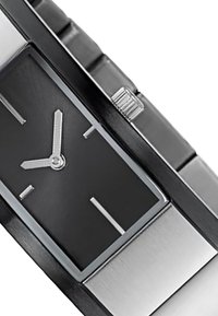 Montre rectangulaire noire avec des accents argentés, affichant un cadran minimaliste, un bracelet en acier inoxydable et un bouton-poussoir texturé sur le côté.