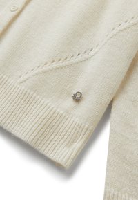 Krémový vlněný cardigan s pletenou texturou, zapínání na knoflíky a stříbrným zdobením na přední straně.