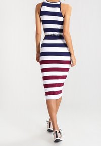 Randig midiklänning med horisontella marinblå, vita och vinröda ränder, med en figurnära passform och ett bälte i midjan.
