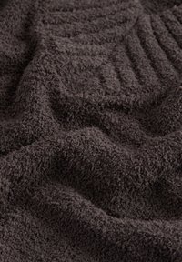 Tumepruun tekstuuriga rätik, mille pealispind on pehme ja siidine, iseloomustatud kohevate, aasastega ning mõnevõrra reljeefsete mustritega.