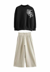 Sweatshirt noir avec texte blanc et motif floral, associé à un pantalon large à rayures crème avec une taille élastique.