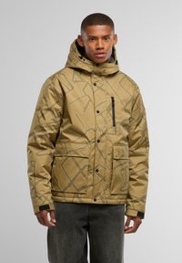 Giacca marrone a fantasia con cappuccio, dotata di una zip frontale e due tasche grandi. Realizzata in un materiale liscio e resistente all'acqua.