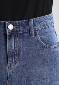 Džíny z denimu, světle modré barvy, s klasickým střihem, s knoflíkovým zapínáním, viditelným švem a přední kapsou.