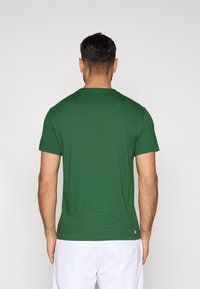 Camiseta verde de manga corta con cuello redondo, hecha de algodón suave, con un corte clásico y detalles mínimos.