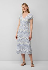 Abito a maniche corte con scollo a V in un motivo a zigzag blu, viola e giallo. Lunghezza a metà polpaccio con vita aderente e parte inferiore fluida.