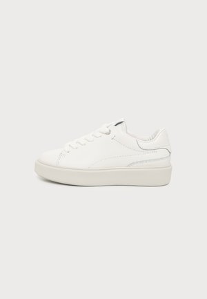 Hvid lav sneaker med snørelukning og tyk sål, vist fra siden mod en ensfarvet lys baggrund.