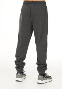 Grå sweatpants med elastisk midja och mudd, med sidofickor. Matchade med grå och svarta sneakers med vita sulor.