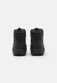 Schwarze Wanderschuhe mit strukturierter Oberfläche, hohem Knöchelsupport und robuster Sohle. Mit Branding an der Seite und verstärktem Fersenbereich.