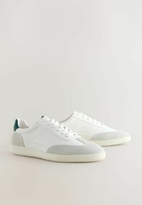 Baskets blanches avec cuir texturé et accents en daim. Comprend un onglet de talon vert, des lacets ronds et une semelle en caoutchouc. Design minimaliste.