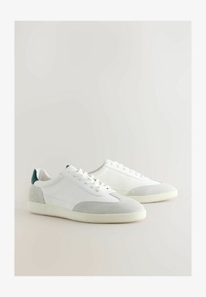 Witte sneakers met een textuur van leer en accenten van suede. Voorzien van een groene hieltab, ronde veters en een rubberen zool. Minimalistisch ontwerp.