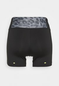 Shorts de sport noirs à taille haute avec un panneau imprimé léopard gris et de petits détails réfléchissants jaunes près des ouvertures des jambes.