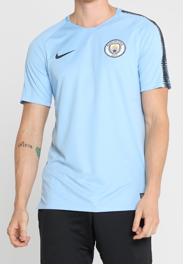 Helles blaues Nike-Sporttrikot mit kurzen Ärmeln, Signatur-Logo und Manchester City-Emblem auf der Brust. Verfügt über strukturierte Details an den Schultern.