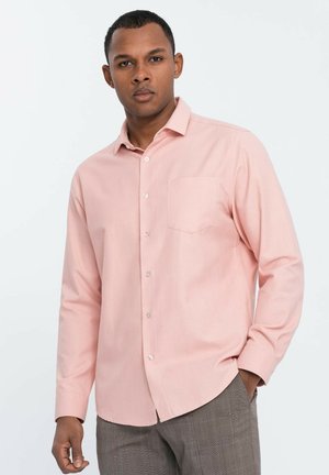 Chemise boutonnée à manches longues rose clair avec une poche poitrine, présentant un col classique et une texture de tissu lisse.