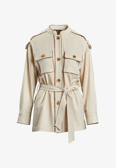 Jachetă bej cu guler chinezesc, două buzunare frontale, închidere cu nasturi aurii și țesătură contrastantă maro. Are o talie cu curea.