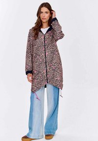 Džínová bunda s leopardím potiskem a růžovými akcenty, černým obložením a pružnými knoflíky. Dlouhé rukávy a volný střih, spárováno s širokými modrými džínami.