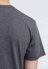 Szara bawełniana koszulka z okrągłym dekoltem, krótkimi rękawami oraz gładką fakturą. Widok z tyłu prezentuje prosty, bezszwowy design.