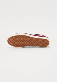 Talpa de pantof cu o bază din cauciuc texturat, având un model în diamant și o suprafață superioară din suede maroniu, cu o dungă albă pe lateral.